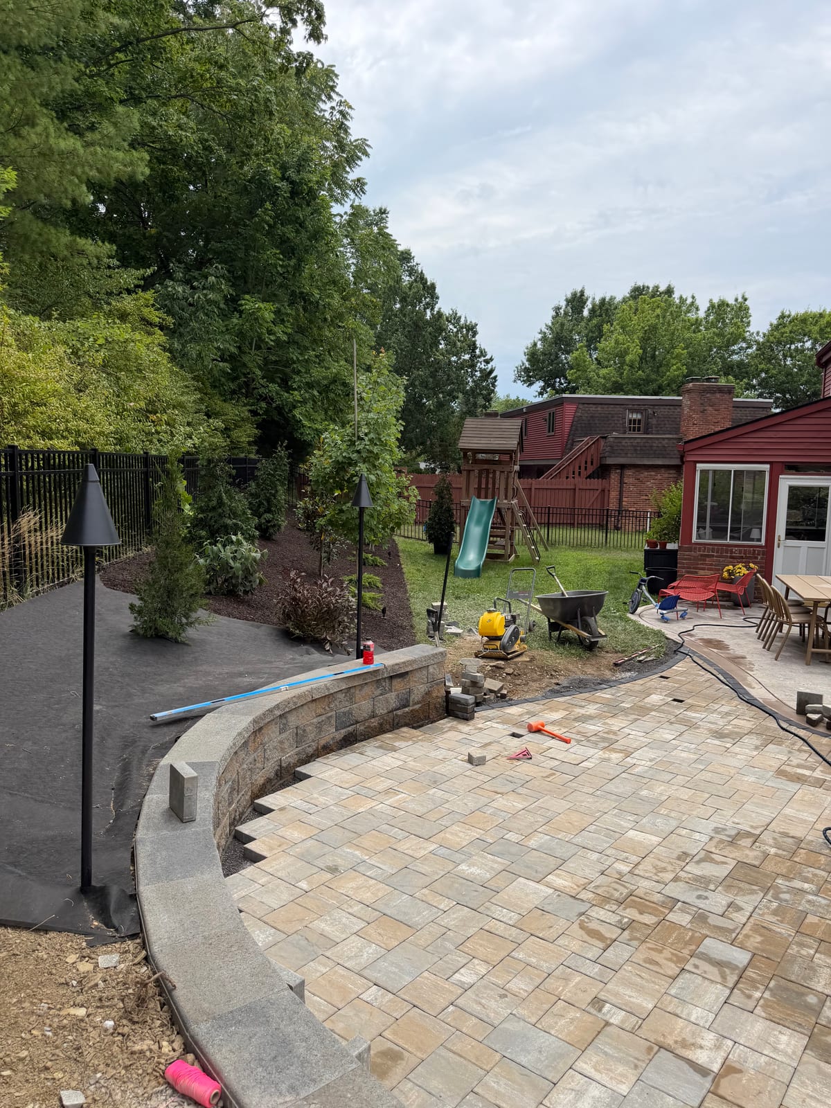Curved paver retaining wall with integrated landscape lighting during a Betschart hardscape build